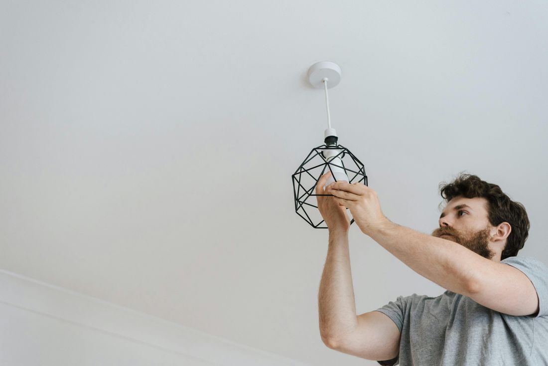Électricien installant un luminaire au plafond